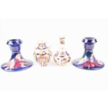 A pair of Moorcroft tubelined dwarf candlesticks, decorated in the hibiscus pattern on a blue