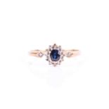 A 9ct yellow gold, diamond, and sapphire cluster ring, set with a mixed oval-cut sapphire, within