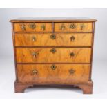 An 18th century figured walnut chest of drawers, the top with oval inset burr walnut panel, cross