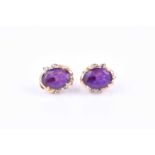 A pair of yellow gold, amethyst, and diamonds earrings, each set with a mixed oval-cut within a
