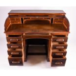 A 1920s oak roll top clerk's desk, by George Blake & Co, Oxford, the top opening to reveal a