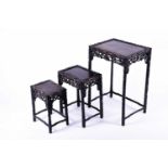 A Chinese carved hardwood nest of three occasional tables, the frames carved with prunus root