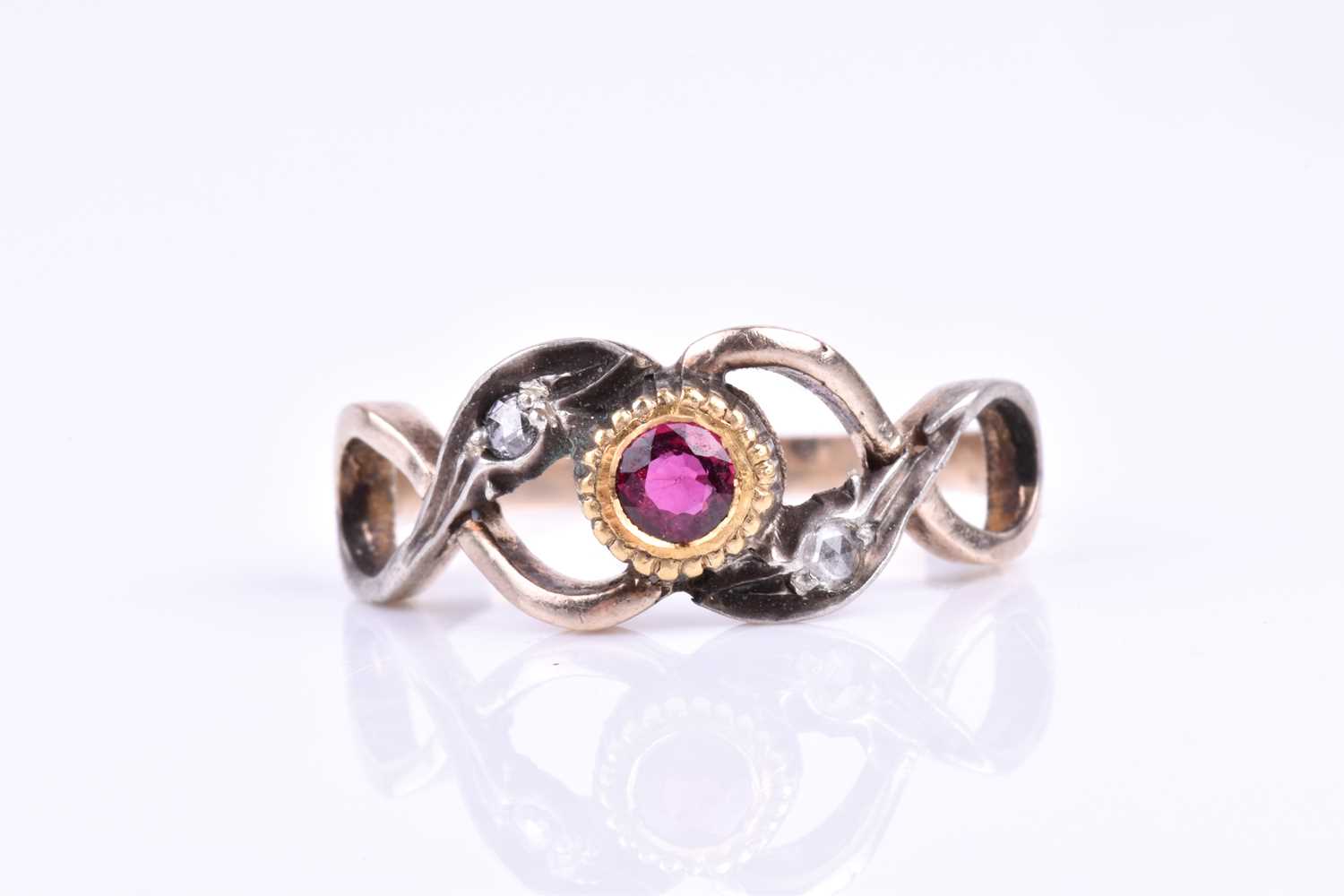 A yellow metal, silver, diamond, and ruby ring, centred with a mixed round-cut ruby in a yellow gold