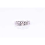 A three stone diamond ring, set with a round brilliant-cut 0.33 carat diamond, flanked with two