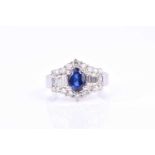 An 18ct white gold, diamond, and sapphire ring, set with a mixed oval-cut sapphire flanked with