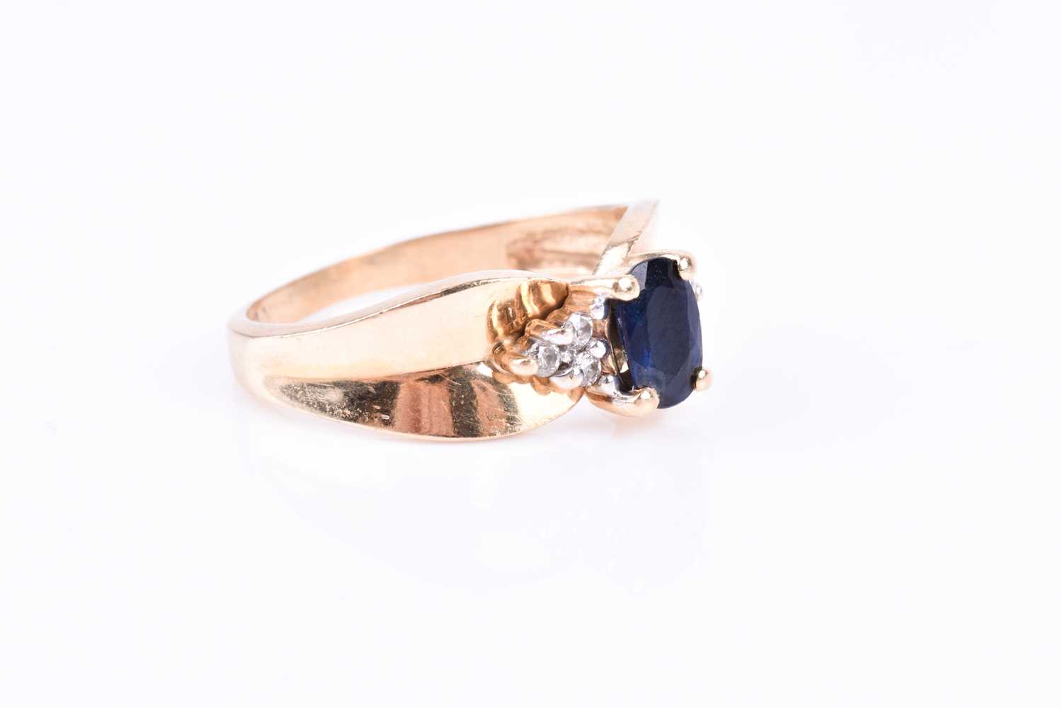 A yellow metal and sapphire ring, the pinched mount centred with an oval-cut sapphire and flanked - Image 2 of 3