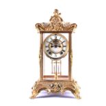 An early 20th century gilt metal four glass mantel clock, modelled with rococo style scroll and leaf