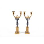 A pair of French Empire period ormolu and bronze twin branch candelabra, each with winged female
