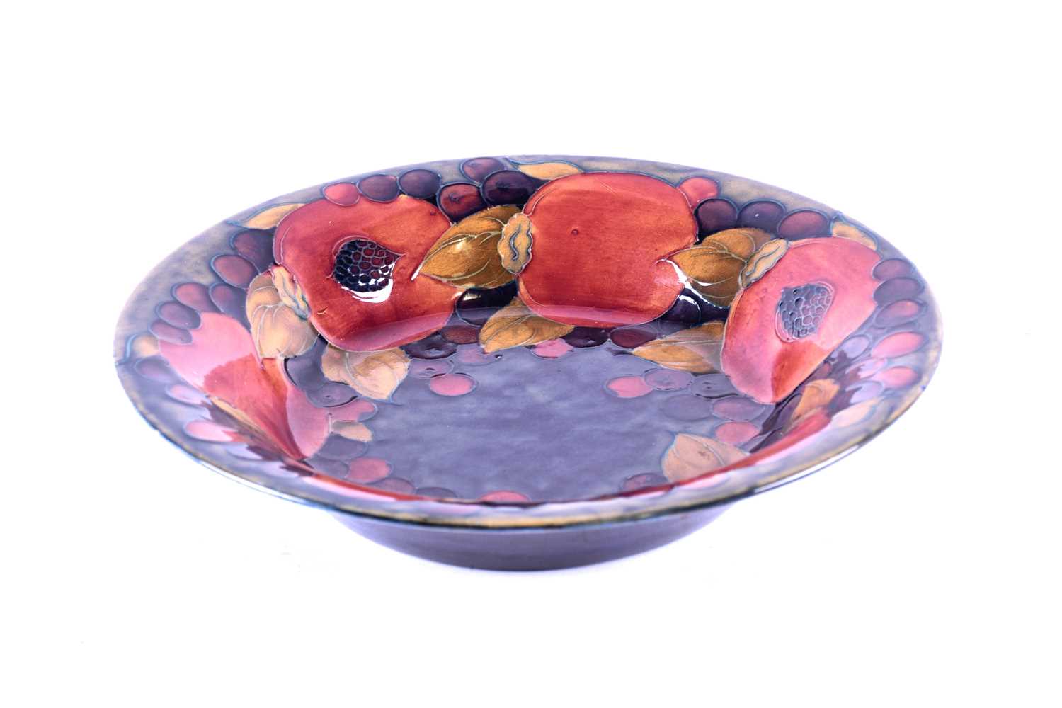 A William Moorcroft 'Pomegranate' bowl, circa 1930, the bowl decorated with leaves and berries