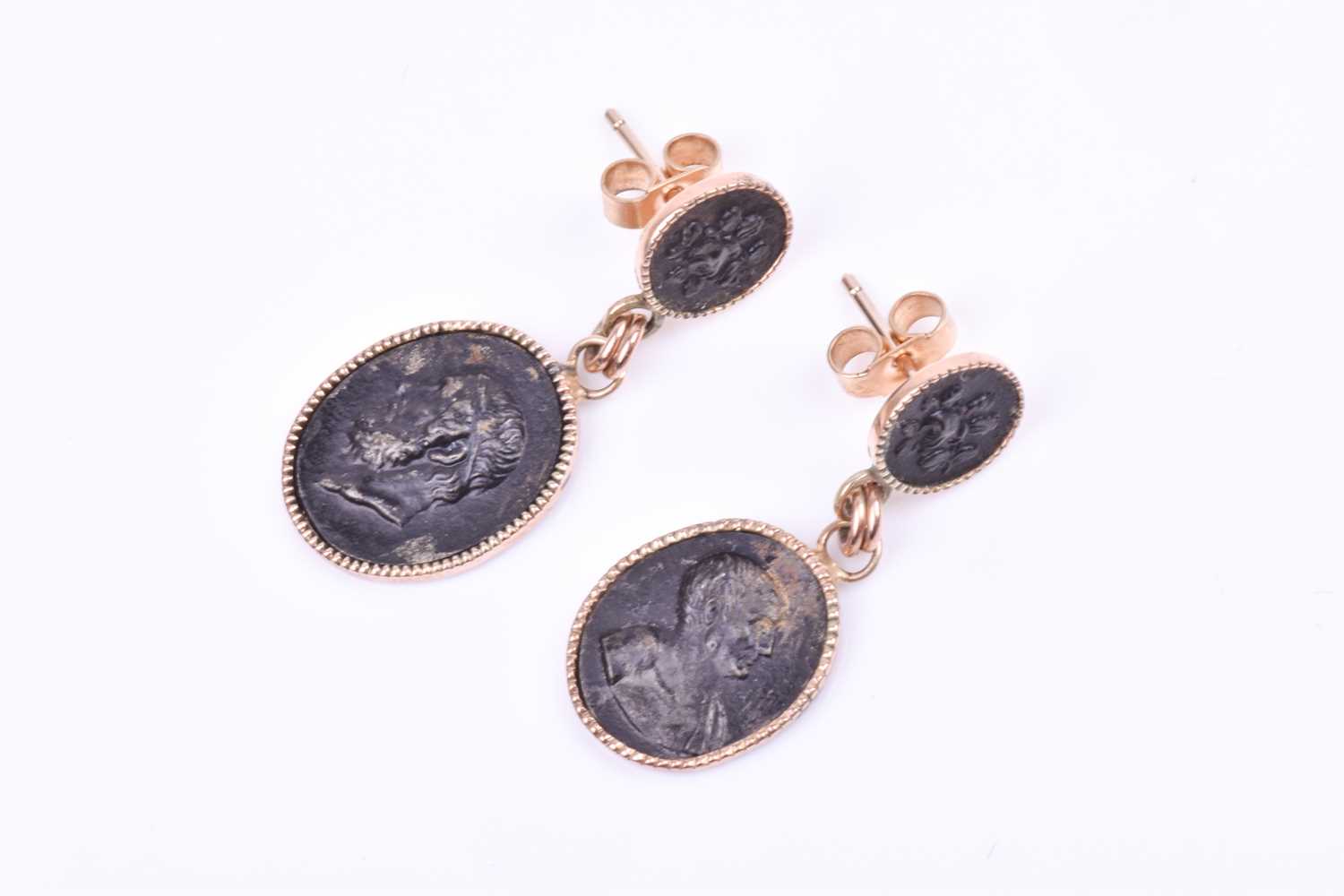 A pair of yellow metal cameo drop earrings, each set with an oval metallic cameo depicting a