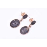 A pair of yellow metal cameo drop earrings, each set with an oval metallic cameo depicting a