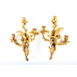A pair of rococo style ormolu wall sconces, each with three-branch lampholders, formed as