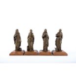 A group of four gilt metal figures; three apostles and another, each mounted to a wooden stand, each