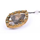 An unusual 19th century gilt metal pendant souvenir, enclosing a piece of rock from Lourdes, held in