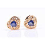 A pair of diamond and sapphire heart-shaped earrings, each set with a heart-shaped sapphire within a