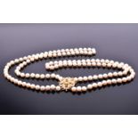 A double strand cultured pearl necklace, with gilt metal, pearl, and ruby floral cluster clasp,