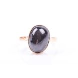 A yellow metal and black chrysoberyl ring, the oval cabochon with indistinct asterism, bezel-set,