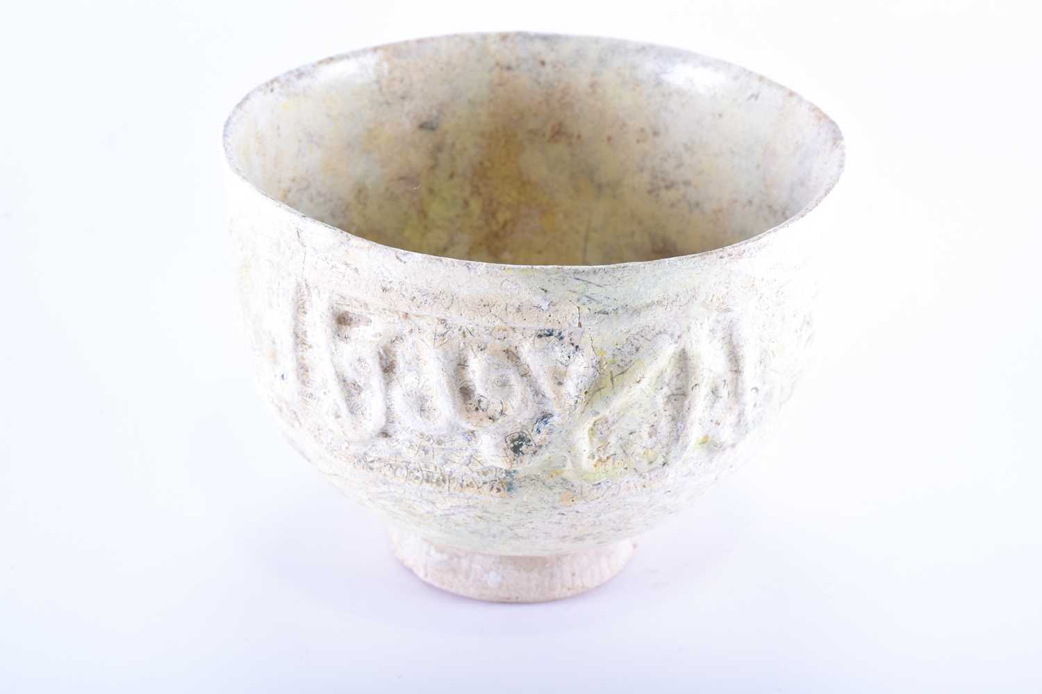 A medieval Islamic pottery bowl with moulded calligraphy,11th - 15th century, with a band of