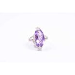 An 18ct white gold, diamond, and amethyst ring, set with a faceted marquise-cut amethyst, surmounted