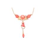 A yellow metal and coral drop pendant necklace, with three rounded coral beads, a coral figa pendant