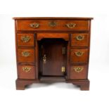 A George III mahogany knee hole desk, the top with shaped rim over a long frieze drawer, concealed