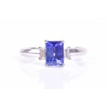 A platinum, diamond, and tanzanite ring, set with a mixed rectangular-cut tanzanite, approximately