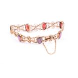 A 9ct yellow gold and garnet bracelet, the stylised articulated links inset with mixed oval-cut