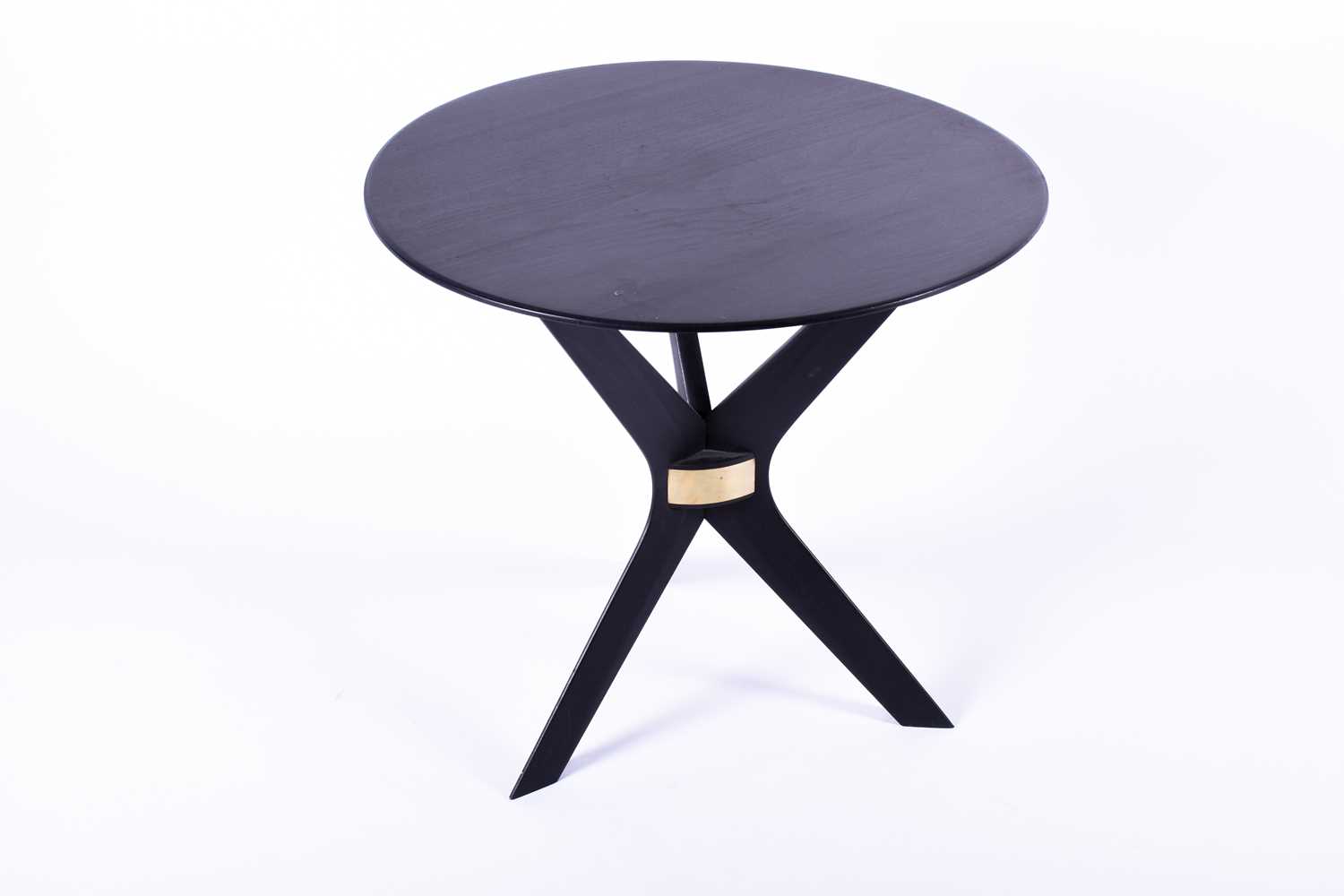 A Birgit Israel ebonised side table, the plain circular top supported on boomerang shaped legs, with