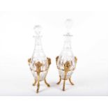 A pair of European early twentieth century cut glass decanters in ormolu stands; the tripod style