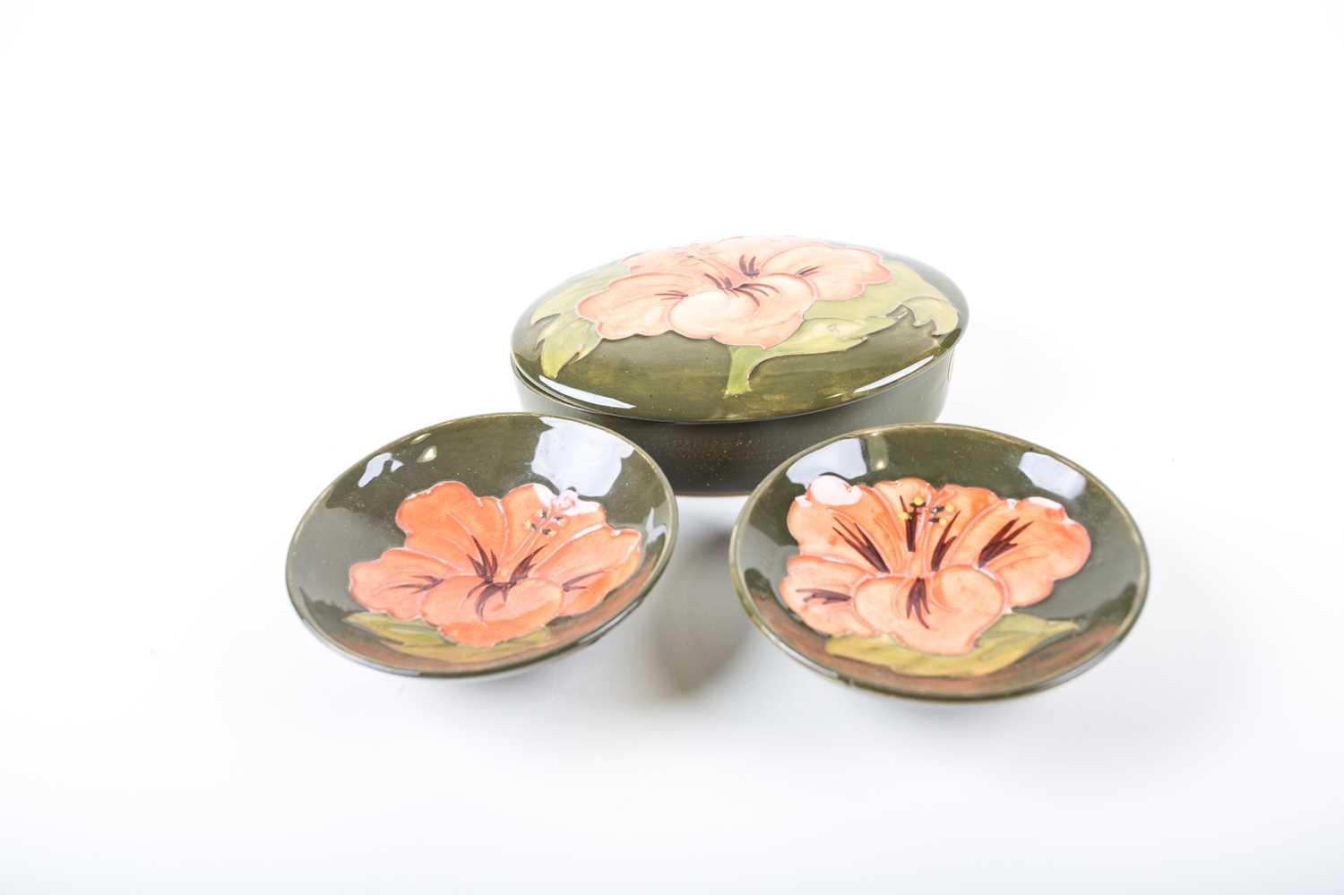 Three items of Moorcroft Hibiscus pattern items, comprising an oval covered bowl, 12.5 cm wide,