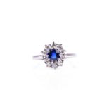 A diamond and sapphire cluster ring, the mixed round-cut sapphire surrounded with a border of