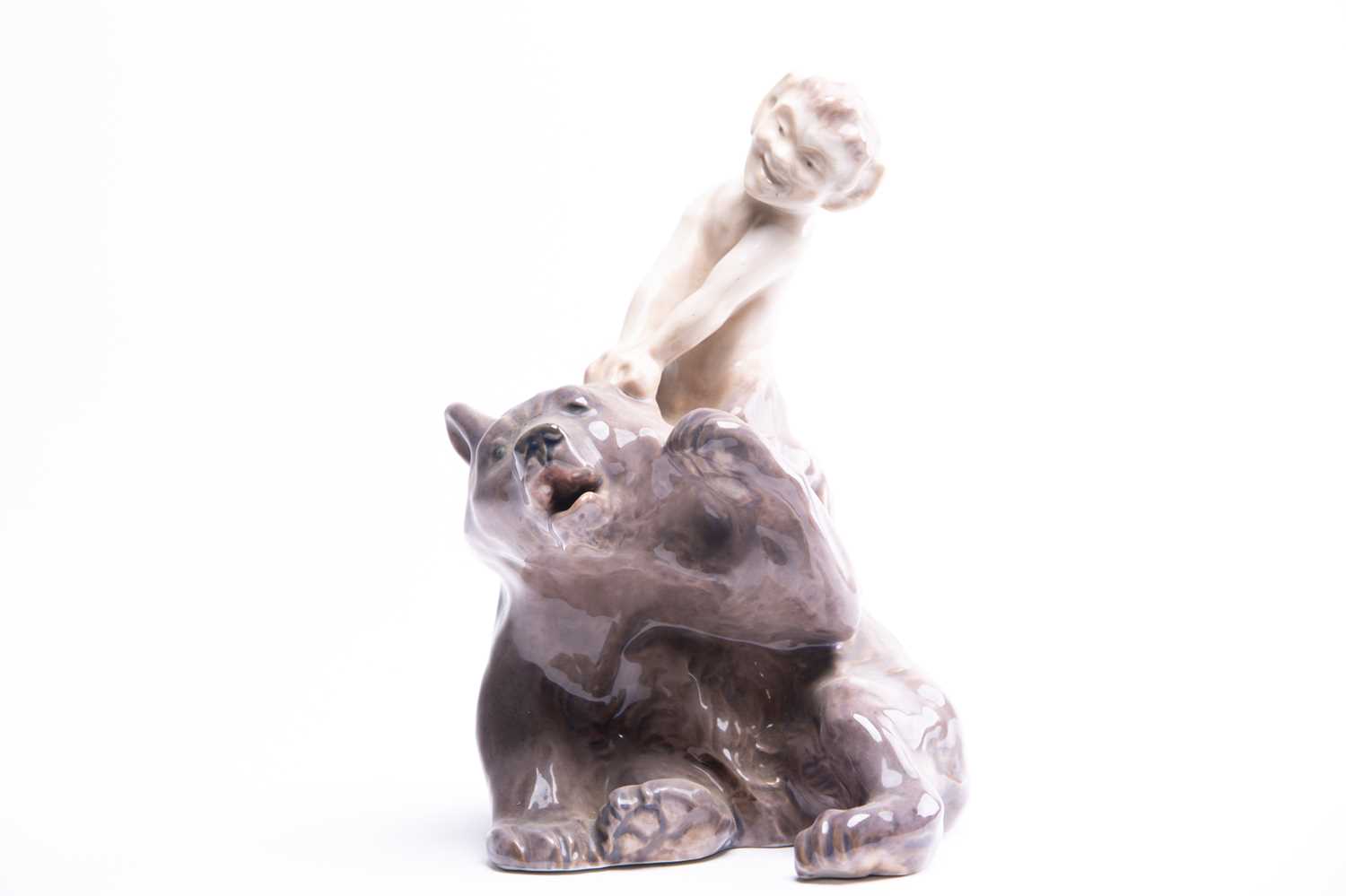 A Royal Copenhagen figure group of a faun sitting on and pulling the ear of a bear, numbered 1804,