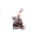 A Royal Copenhagen figure group of a faun sitting on and pulling the ear of a bear, numbered 1804,