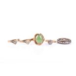 A yellow metal and green hardstone ring, set with an oval cabochon jadeite in stylised four-claw