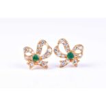 A pair of diamond and emerald metamorphic bow earrings, the ribbon-work set with round brilliant cut