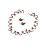 A silver and garnet dress necklace, formed of curved links and floral clusters set with round-cut