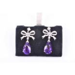 A pair of 18ct white gold, diamond, and amethyst drop earrings, the diamond-set bow-shaped