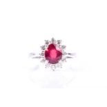 An 18ct white gold, diamond, and ruby cluster ring, set with a mixed oval-cut ruby within a border