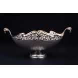 A Continental white metal bowl of boat form, with pierced body and prolific foliate decoration, on a