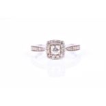 A diamond cluster ring, the cushion shaped cluster set with a central round brilliant cut diamond,