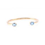 An 18ct gold and blue topaz torque bracelet, the polished angled bangle with oval cut topaz