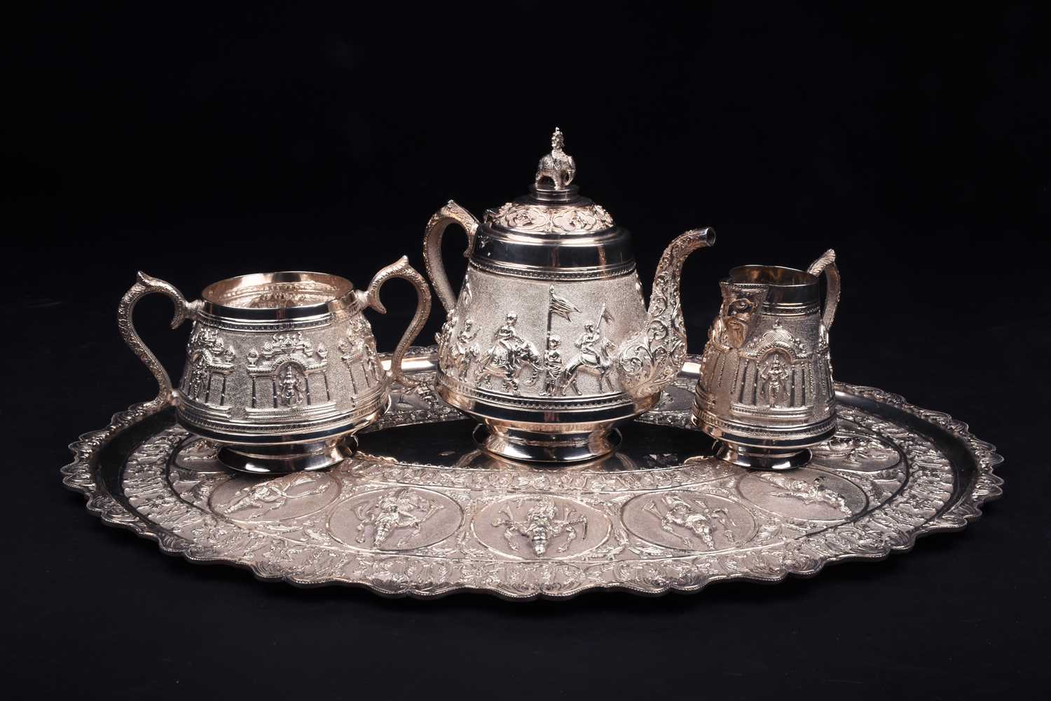 An Indian white metal three-piece teaset and conforming oval tray, 20th century, each decorated with