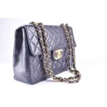 Chanel. A classic single flap black leather quilted handbag, with double gold tone chain and leather