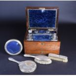 A matched silver-backed dressing table set, comprising a mirror and two brushes, various dates and