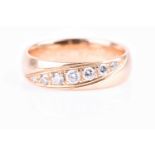 An 18ct yellow gold and diamond wedding band, inset with a graduated row of seven small round-cut