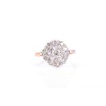 A diamond cluster ring, the central claw mounted round brilliant cut diamond within a border of