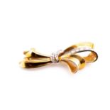 A mid 20th century yellow metal and diamond bow brooch, of scrolled design, set with a line of