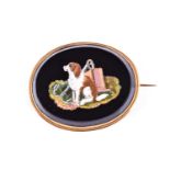 A 19th century Italian yellow metal mounted micro mosaic brooch depicting a patient spaniel, the dog