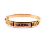 A late Victorian yellow metal, diamond, and ruby bangle bracelet, set with graduated old round-cut