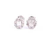 A pair of diamond cluster earrings, the central cut-cornered emerald cut diamond within a border